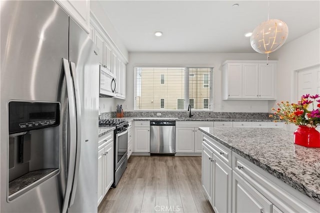 10648 Paramount Blvd, Downey, CA 90241 - kitchen with appliances with stainless steel finishes, white cabinetry, light wood-type flooring, recessed lighting, and light stone countertops