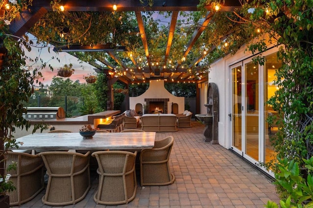 7691 Circulo Sequoia, Carlsbad, CA 92009 - patio terrace at dusk featuring a warm lit fireplace, a patio area, and a pergola