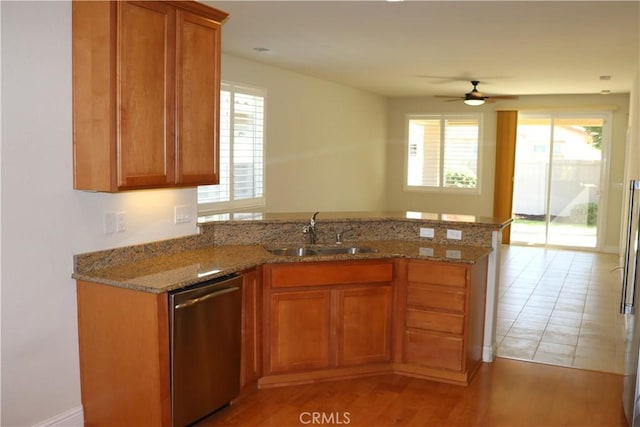 1573 Maple Valley St, Manteca, CA 95336 - kitchen with stainless steel dishwasher, a peninsula, brown cabinetry, a ceiling fan, and light stone countertops