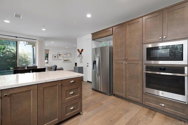 140 Unity Ln, San Marcos, CA 92078 - kitchen featuring appliances with stainless steel finishes, light wood finished floors, recessed lighting, light stone countertops, and dark brown cabinetry