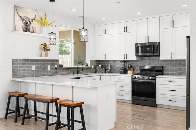 2213 De Mille Rd, Paradise, CA 95969 - kitchen with stainless steel appliances, a peninsula, a kitchen bar, white cabinetry, and backsplash