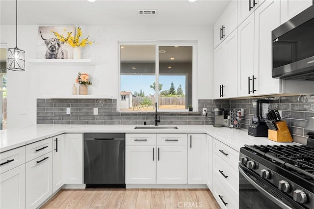 2213 De Mille Rd, Paradise, CA 95969 - kitchen with stainless steel microwave, dishwashing machine, black range with gas stovetop, open shelves, and light stone countertops