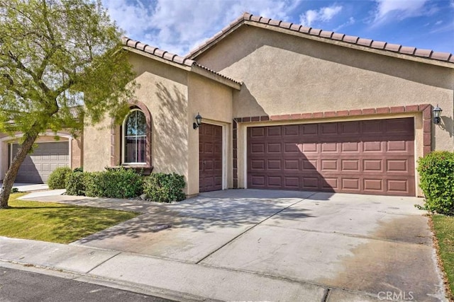 82756 Burnette Dr, Indio, CA 92201 - mediterranean / spanish house featuring an attached garage, concrete driveway, stucco siding, and a tiled roof