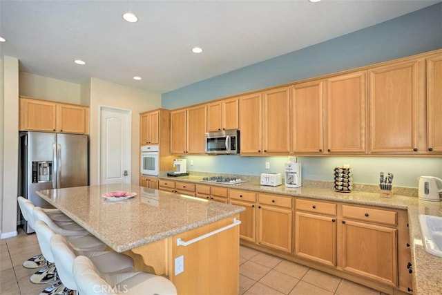 82756 Burnette Dr, Indio, CA 92201 - kitchen featuring stainless steel appliances, light tile patterned flooring, a center island, light stone counters, and recessed lighting