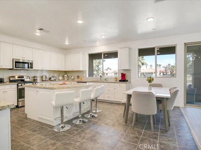 82676 Burnette Dr, Indio, CA 92201 - kitchen with stainless steel appliances, a kitchen island, backsplash, white cabinetry, and recessed lighting