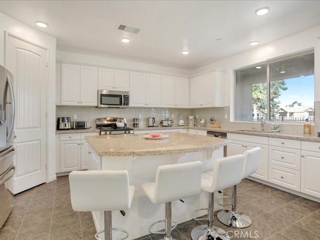 82676 Burnette Dr, Indio, CA 92201 - kitchen with stainless steel appliances, decorative backsplash, a center island, white cabinetry, and recessed lighting