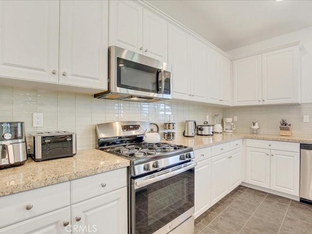 82676 Burnette Dr, Indio, CA 92201 - kitchen featuring appliances with stainless steel finishes, decorative backsplash, white cabinets, and light stone countertops