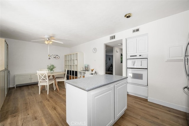 4481 Larwin Ave, Cypress, CA 90630 - kitchen featuring white double oven, ceiling fan, white cabinets, a kitchen island, and wood finished floors