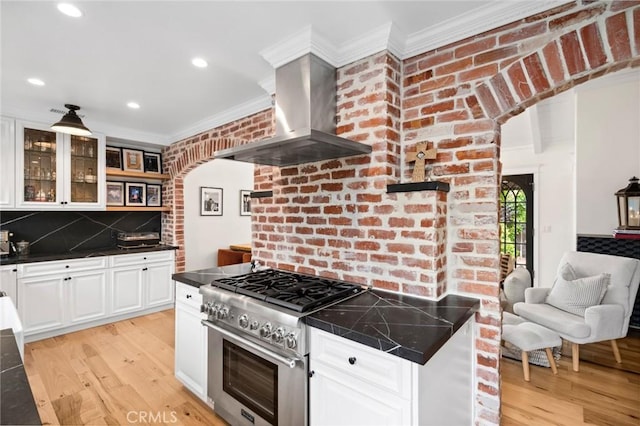 615 Seaview St, Laguna Beach, CA 92651 - kitchen featuring wall chimney exhaust hood, high end range, crown molding, light wood finished floors, and glass insert cabinets