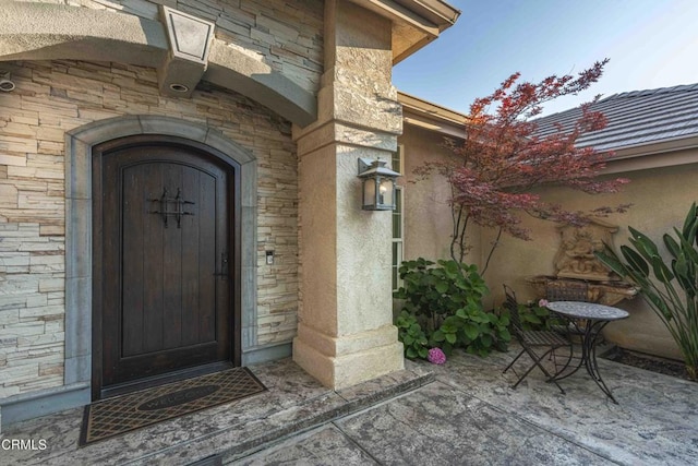 13115 Monarch Palm Ave, Bakersfield, CA 93314 - property entrance with stone siding, a patio area, and stucco siding
