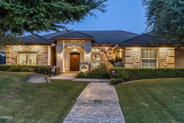 13115 Monarch Palm Ave, Bakersfield, CA 93314 - view of front of property featuring stone siding, a front yard, and a tile roof
