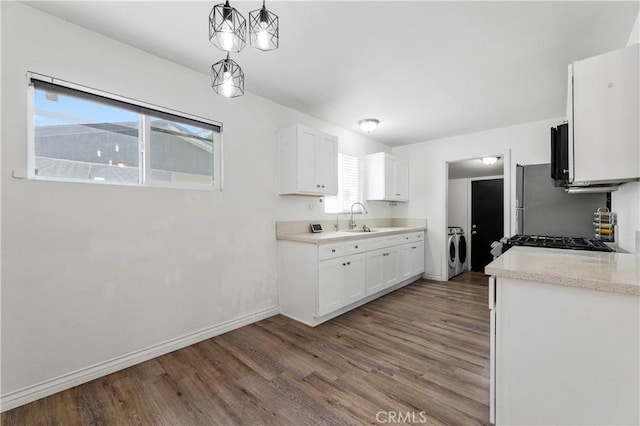 455 E Wilson St, Rialto, CA 92376 - kitchen with independent washer and dryer, wood finished floors, white cabinetry, and decorative light fixtures