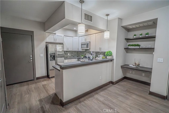 24595 Town Center Dr Unit 3205, Valencia, CA 91355 - kitchen with stainless steel appliances, white cabinets, dark countertops, a peninsula, and backsplash