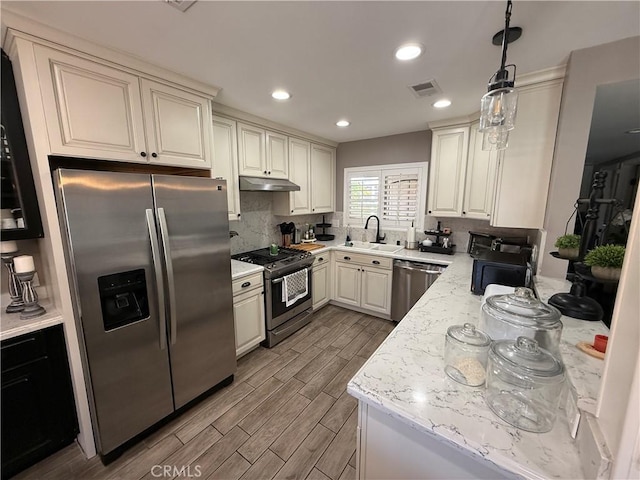 1053 Border Ave, Corona, CA 92882 - kitchen with appliances with stainless steel finishes, decorative backsplash, wood finished floors, under cabinet range hood, and hanging light fixtures