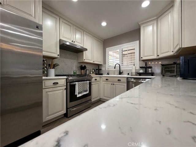 1053 Border Ave, Corona, CA 92882 - kitchen with appliances with stainless steel finishes, under cabinet range hood, tasteful backsplash, recessed lighting, and light stone countertops
