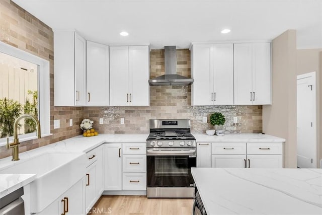 22461 Silver Spur, Lake Forest, CA 92630 - kitchen featuring wall chimney exhaust hood, stainless steel gas range, light stone countertops, white cabinets, and tasteful backsplash
