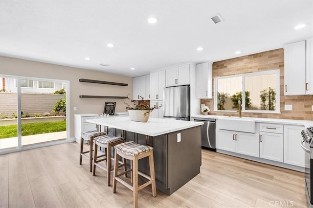 22461 Silver Spur, Lake Forest, CA 92630 - kitchen with stainless steel appliances, a kitchen bar, white cabinets, a center island, and recessed lighting