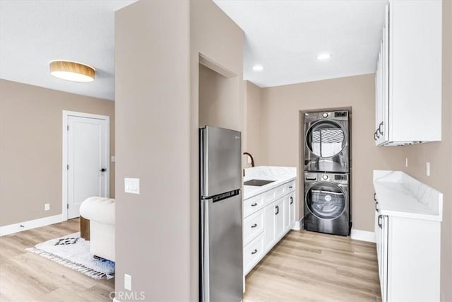 22461 Silver Spur, Lake Forest, CA 92630 - kitchen featuring freestanding refrigerator, light countertops, stacked washer and clothes dryer, white cabinets, and light wood-type flooring