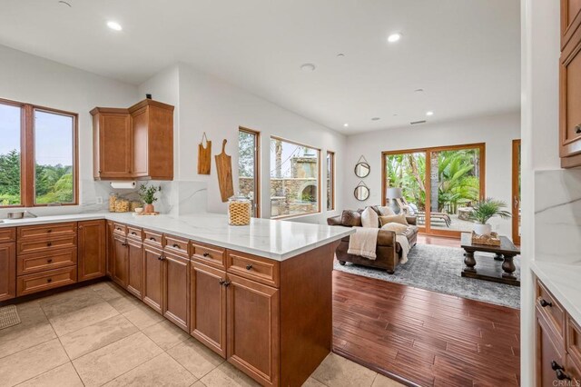 4149 Manchester Ave, Encinitas, CA 92024 - kitchen featuring a peninsula, recessed lighting, brown cabinetry, open floor plan, and light tile patterned flooring