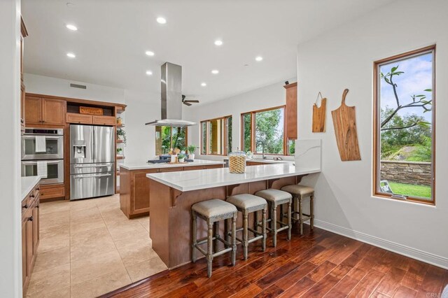4149 Manchester Ave, Encinitas, CA 92024 - kitchen with appliances with stainless steel finishes, a peninsula, island range hood, recessed lighting, and brown cabinetry