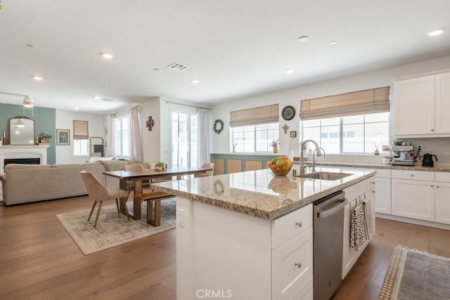 874 Royal Knight Trl, Redlands, CA 92374 - kitchen featuring dishwasher, an island with sink, light wood-style flooring, light stone counters, and white cabinetry