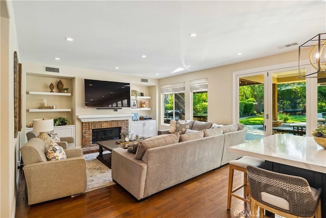 2937 Arboridge Ct, Fullerton, CA 92835 - living area featuring dark wood finished floors, a brick fireplace, recessed lighting, built in shelves, and a chandelier