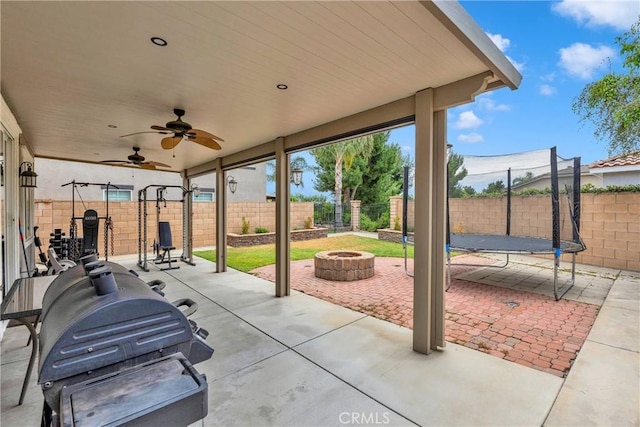 16315 Yorba Linda Ln, Fontana, CA 92336 - fenced backyard with a fire pit, a trampoline, a patio area, a ceiling fan, and area for grilling