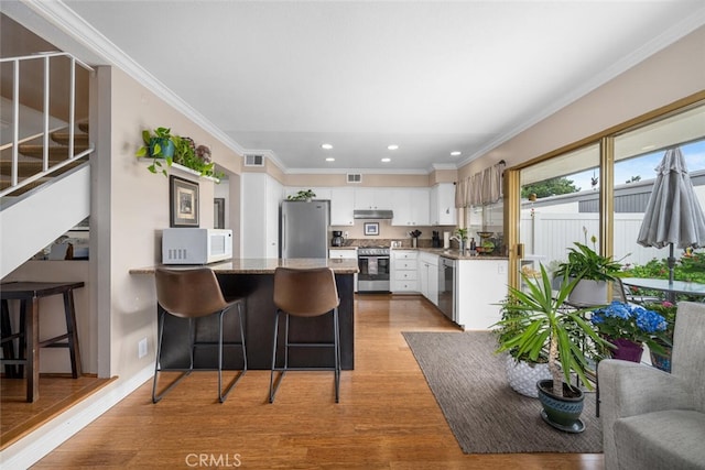 9676 Bloomfield St, Cypress, CA 90630 - kitchen featuring stainless steel appliances, a peninsula, under cabinet range hood, white cabinetry, and recessed lighting