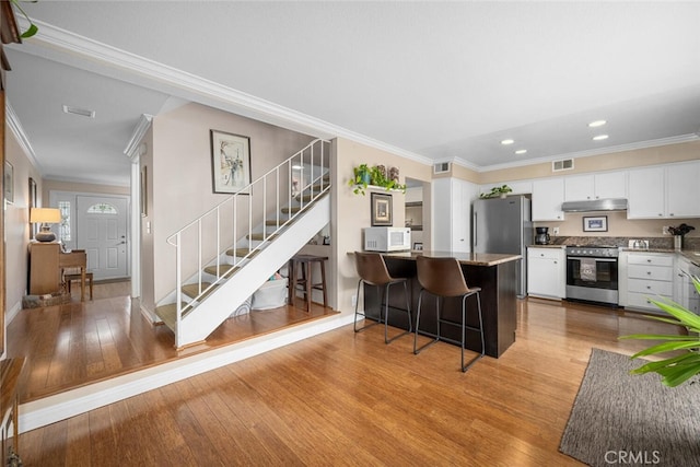 9676 Bloomfield St, Cypress, CA 90630 - kitchen with stainless steel appliances, under cabinet range hood, crown molding, light wood finished floors, and white cabinets