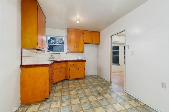 11701 Roseglen St, El Monte, CA 91732 - kitchen with brown cabinets, backsplash, tile counters, and stone finish flooring