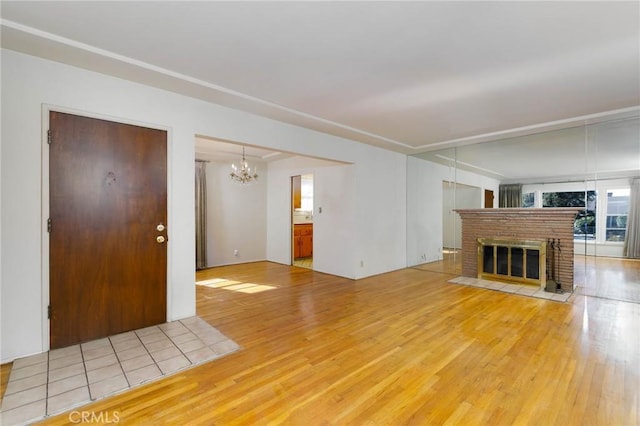 11701 Roseglen St, El Monte, CA 91732 - unfurnished living room with light wood-type flooring, a chandelier, and a brick fireplace