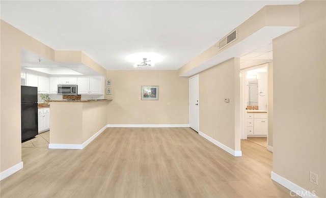 64 N Mar Vista Ave Unit 231, Pasadena, CA 91106 - kitchen with freestanding refrigerator, stainless steel microwave, a peninsula, white cabinetry, and light wood-type flooring