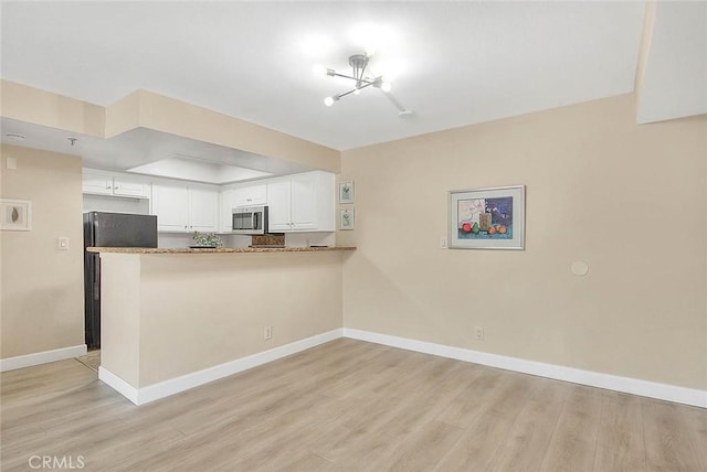64 N Mar Vista Ave Unit 231, Pasadena, CA 91106 - kitchen with stainless steel microwave, white cabinetry, a peninsula, a chandelier, and light wood-style flooring