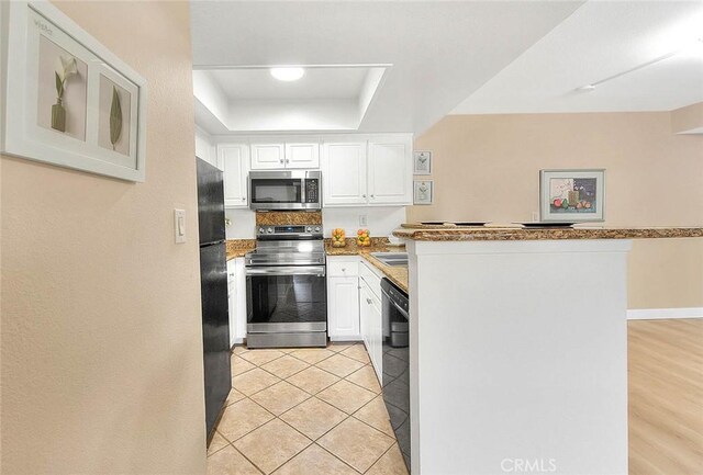 64 N Mar Vista Ave Unit 231, Pasadena, CA 91106 - kitchen with black appliances, a raised ceiling, a peninsula, and white cabinets