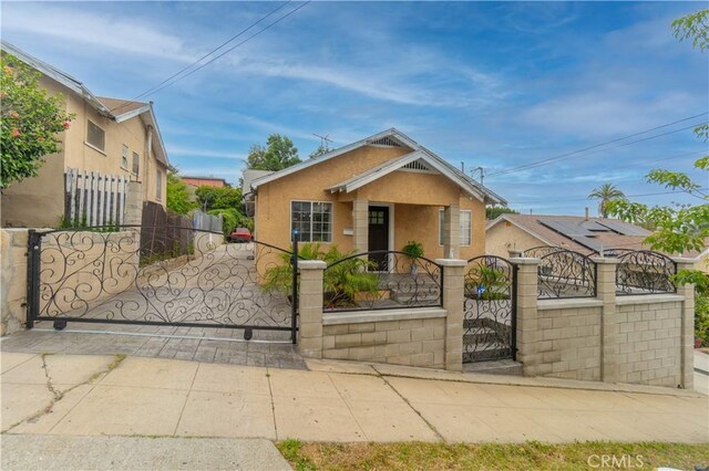 3219 E 6th St, Los Angeles, CA 90023 - bungalow with stucco siding, a fenced front yard, and a gate