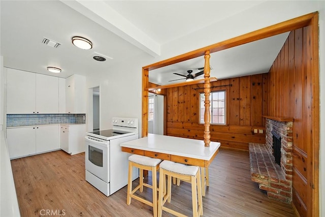 185 N Rodecker Dr, Azusa, CA 91702 - kitchen featuring white range with electric stovetop, light wood-style floors, a ceiling fan, white cabinets, and wooden walls