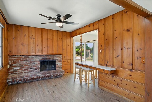 185 N Rodecker Dr, Azusa, CA 91702 - unfurnished dining area with wood finished floors, wooden walls, ceiling fan, and a brick fireplace