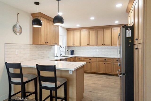 27111 Crews Hill Dr, Menifee, CA 92586 - kitchen with freestanding refrigerator, a peninsula, decorative backsplash, light wood-type flooring, and a breakfast bar
