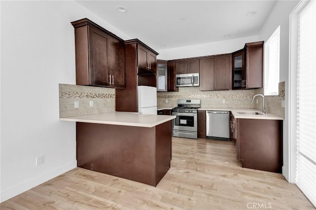 7419 N Mia Ln, Van Nuys, CA 91405 - kitchen with appliances with stainless steel finishes, dark brown cabinets, decorative backsplash, a peninsula, and glass insert cabinets