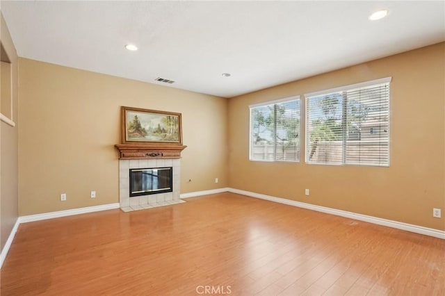 12910 Jersey St, Eastvale, CA 92880 - unfurnished living room featuring light wood-style floors, healthy amount of natural light, a tile fireplace, and recessed lighting