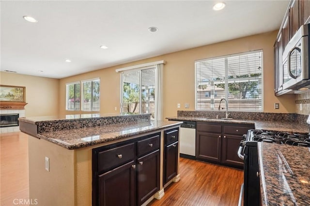 12910 Jersey St, Eastvale, CA 92880 - kitchen with black range with gas stovetop, dishwasher, stainless steel microwave, a center island, and dark stone countertops