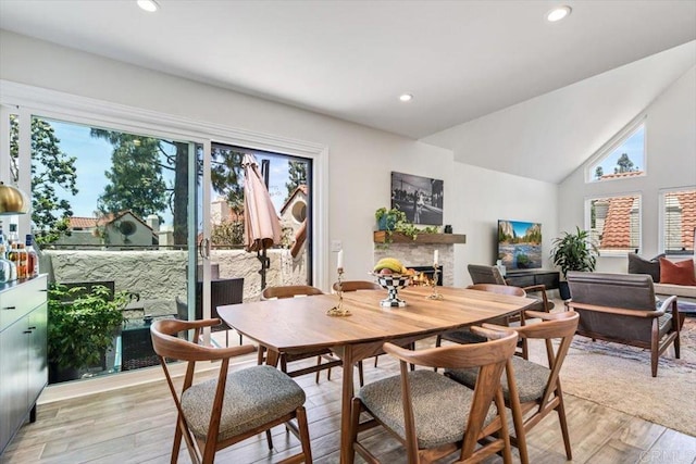 17915 Caminito Pinero Unit 264, San Diego, CA 92128 - dining area with a warm lit fireplace, light wood-type flooring, vaulted ceiling, and recessed lighting