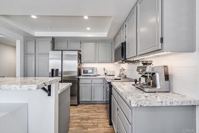 17915 Caminito Pinero Unit 264, San Diego, CA 92128 - kitchen featuring stainless steel appliances, gray cabinetry, a tray ceiling, light wood-style flooring, and recessed lighting