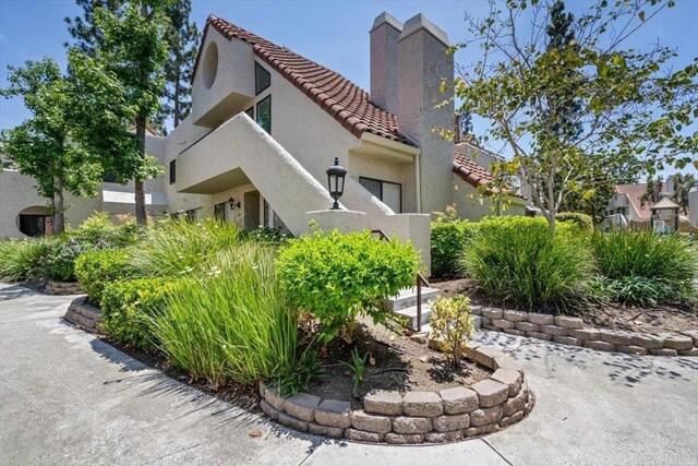 17915 Caminito Pinero Unit 264, San Diego, CA 92128 - view of home's exterior with a tiled roof, a chimney, and stucco siding