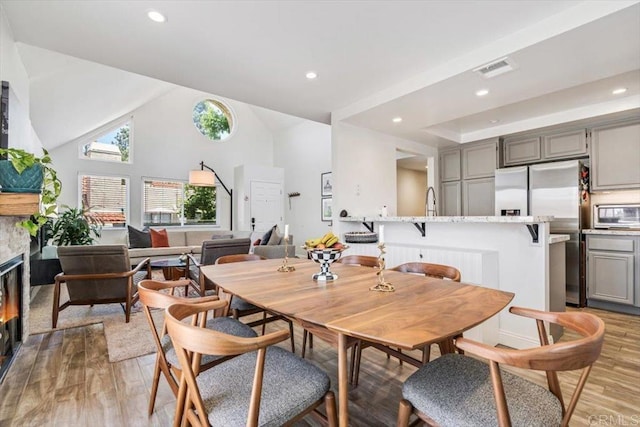 17915 Caminito Pinero Unit 264, San Diego, CA 92128 - dining area featuring light wood finished floors, recessed lighting, a glass covered fireplace, and vaulted ceiling
