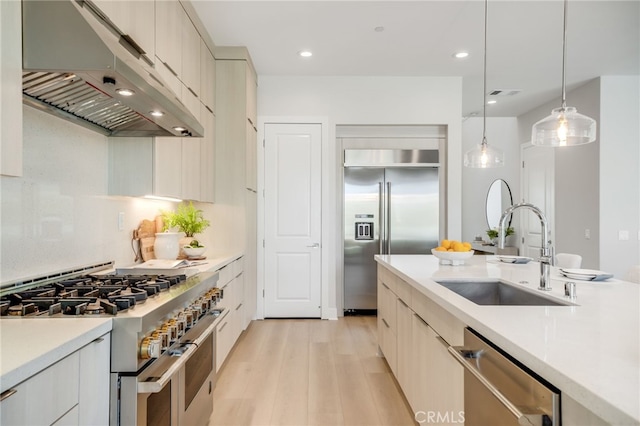 211 Wild Flower, Lake Forest, CA 92630 - kitchen featuring range hood, high end appliances, light wood-style floors, light countertops, and decorative light fixtures