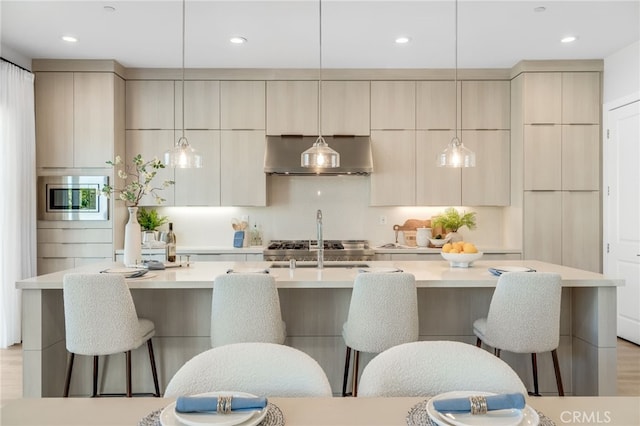211 Wild Flower, Lake Forest, CA 92630 - kitchen with wall chimney exhaust hood, modern cabinets, stainless steel microwave, a center island with sink, and recessed lighting