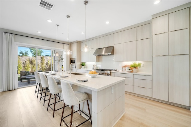 211 Wild Flower, Lake Forest, CA 92630 - kitchen with ventilation hood, modern cabinets, a center island with sink, a breakfast bar area, and light wood-style flooring