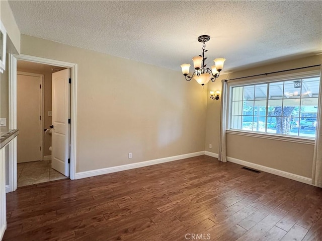 2817 San Verbena Way, Chico, CA 95973 - empty room featuring a chandelier, dark wood-style floors, and a textured ceiling