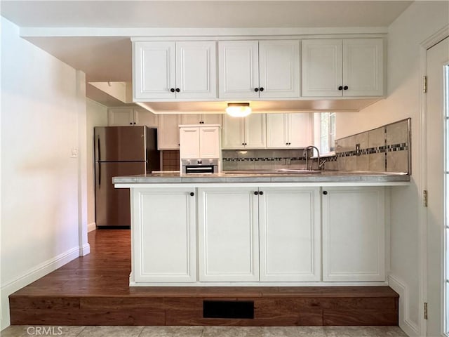 2817 San Verbena Way, Chico, CA 95973 - kitchen featuring appliances with stainless steel finishes, backsplash, white cabinets, a peninsula, and dark wood-type flooring
